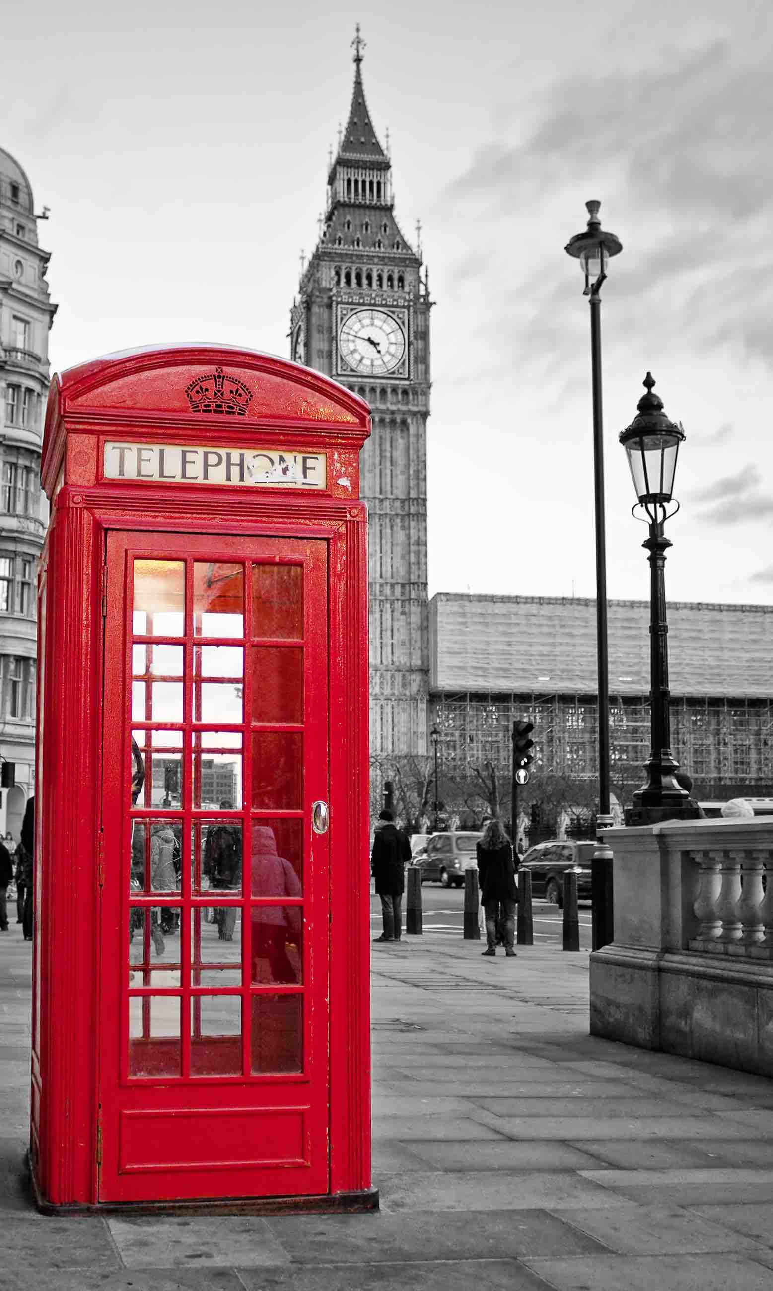 A  traditional red phone booth in London with the Big Ben in a black and white background